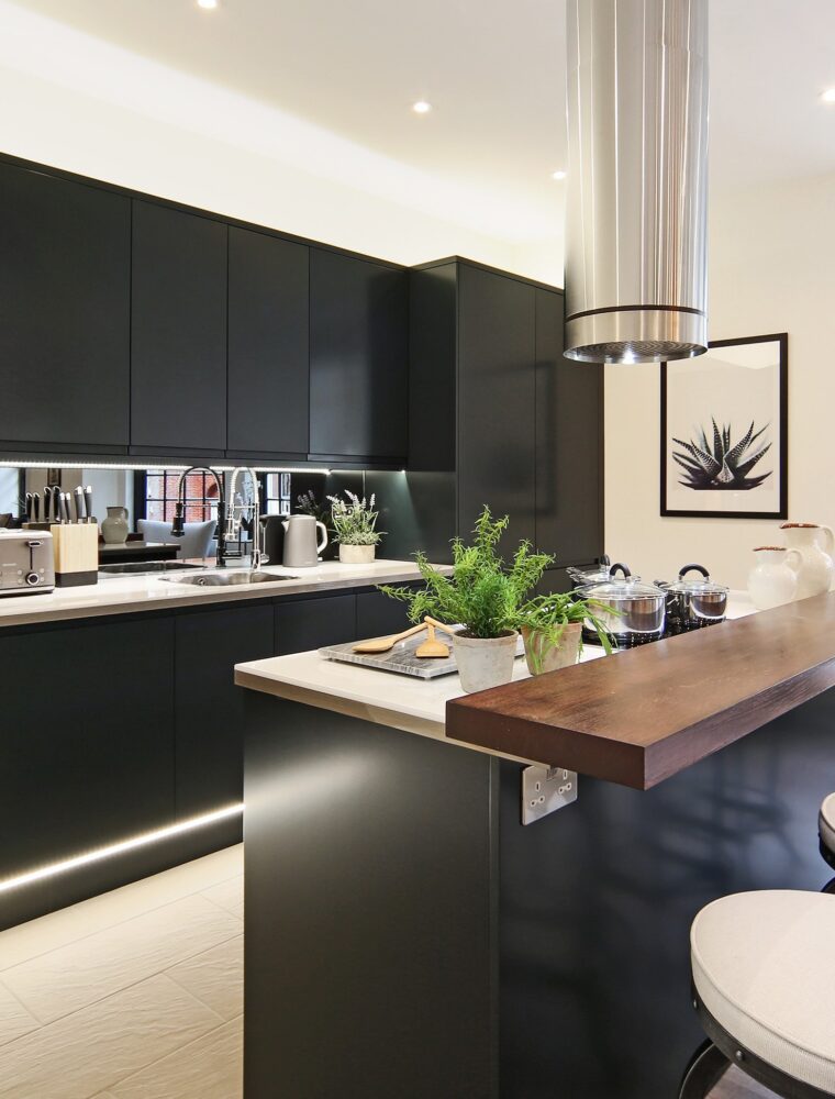 An investment property in London with a black kitchen with kitchen island feature, hard wood floors and built in lights.