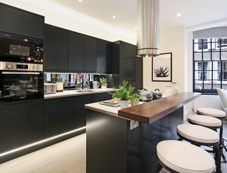 An investment property in London with a black kitchen with kitchen island feature, hard wood floors and built in lights. Purchased by a London Buying Agent