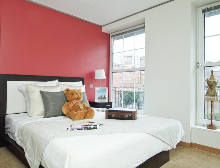 A bedroom with a red theme wall, a double bed with two bedside tables.