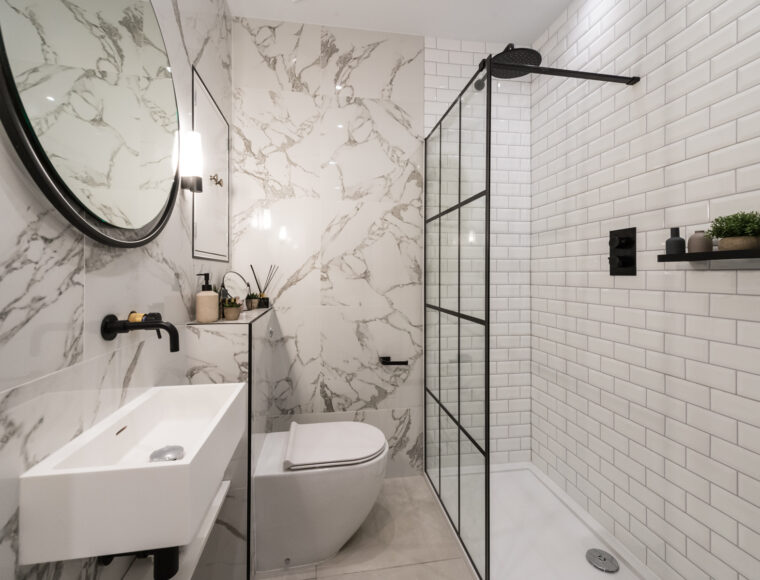 A bathroom with marble walls, and a walk in shower.