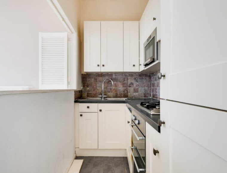 A narrow kitchen with a opening into the living room.