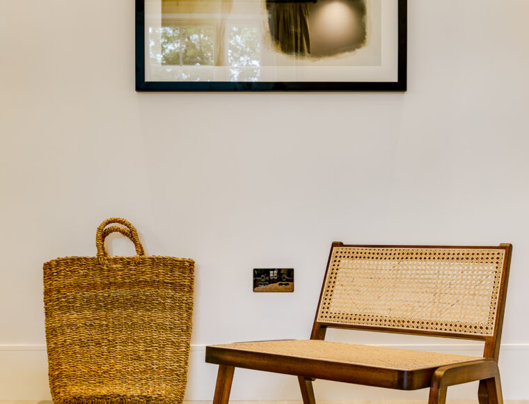 A seating area with an arm chair, with a large bag against the wall featuring wall art.