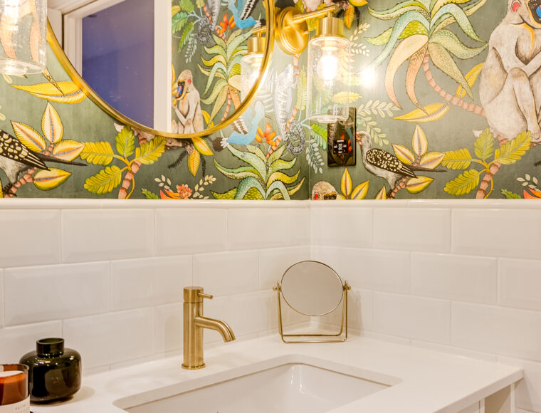 A tropical themed bathroom with a sink cabinet and circle mirror placed on the wall.