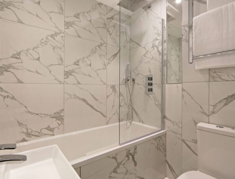 A bathroom with marble walls, with a bathtub and shower.
