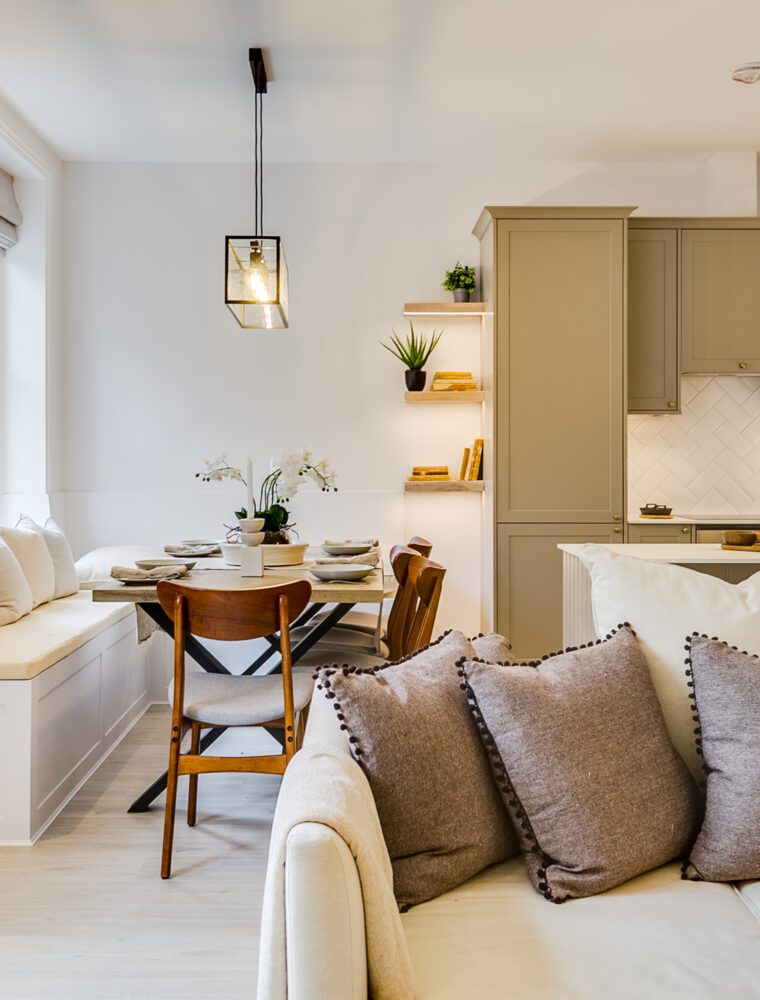 A luxury buy-to-let property in London featuring an open plan kitchen and living room with cream-coloured sofas and chairs, with a wooden dining table.