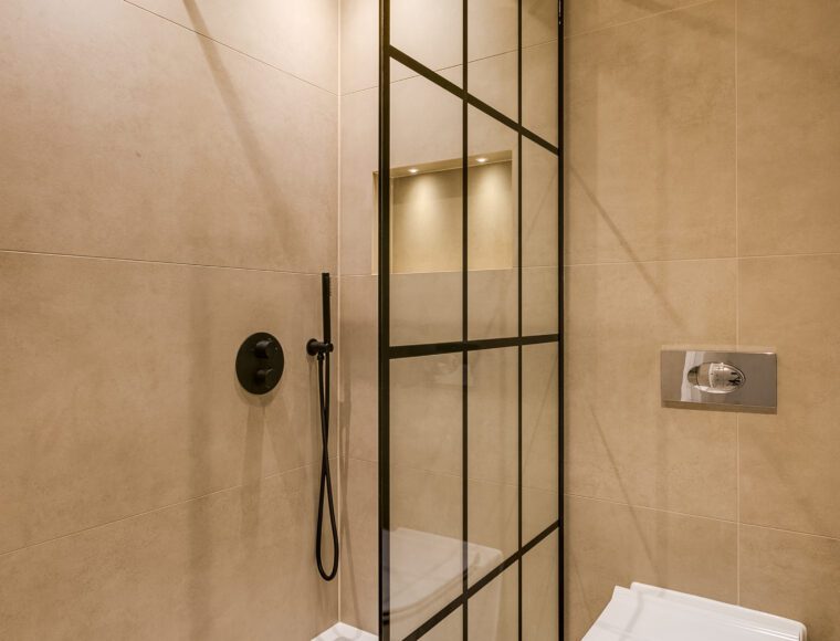 A bathroom, with a walk in shower and built in shelf.