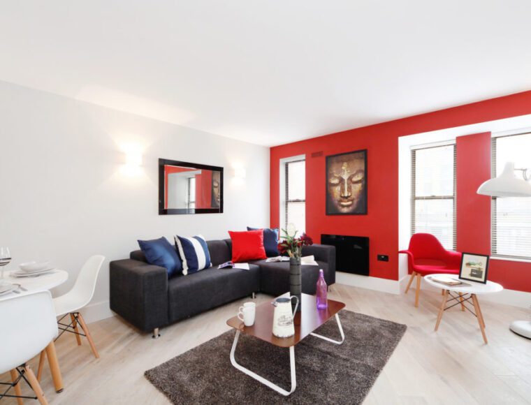 Living room space with a red theme wall, sofas, coffee tables and dining area.